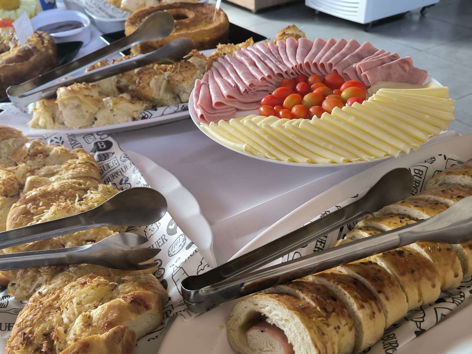 Mesa do buffet de café da manhã do Paulo's com pães, frios e bolos